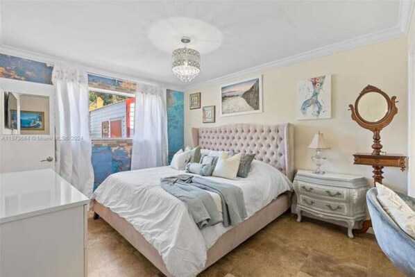 Ein Schlafzimmer mit einem großen Bett, einem Schminktisch, einem Spiegel und Bildern an den Wänden.