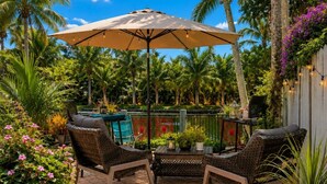 Une terrasse extérieure aménagée avec des meubles en osier, une table et un parasol.