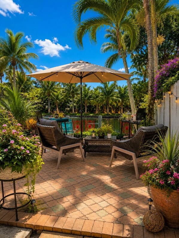 Une terrasse extérieure aménagée avec des meubles en osier, une table et un parasol.