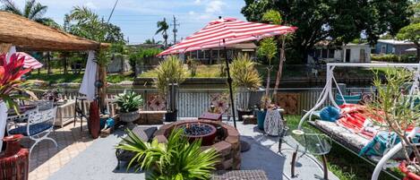An outdoor patio area with a fire pit, seating, and umbrellas.