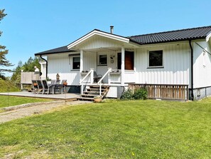 Ein weißes, zweistöckiges Haus mit Veranda, Terrasse und kleinem Garten.