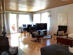 Ein Wohnzimmer mit Fernseher, Sitzgelegenheiten und einem Essbereich mit Tisch und Stühlen.