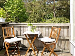 A wooden deck with two wooden chairs and a small table, surrounded by a wooden fence and greenery. - 6 Person Holiday Home in Uddevalla (Uddevalla)