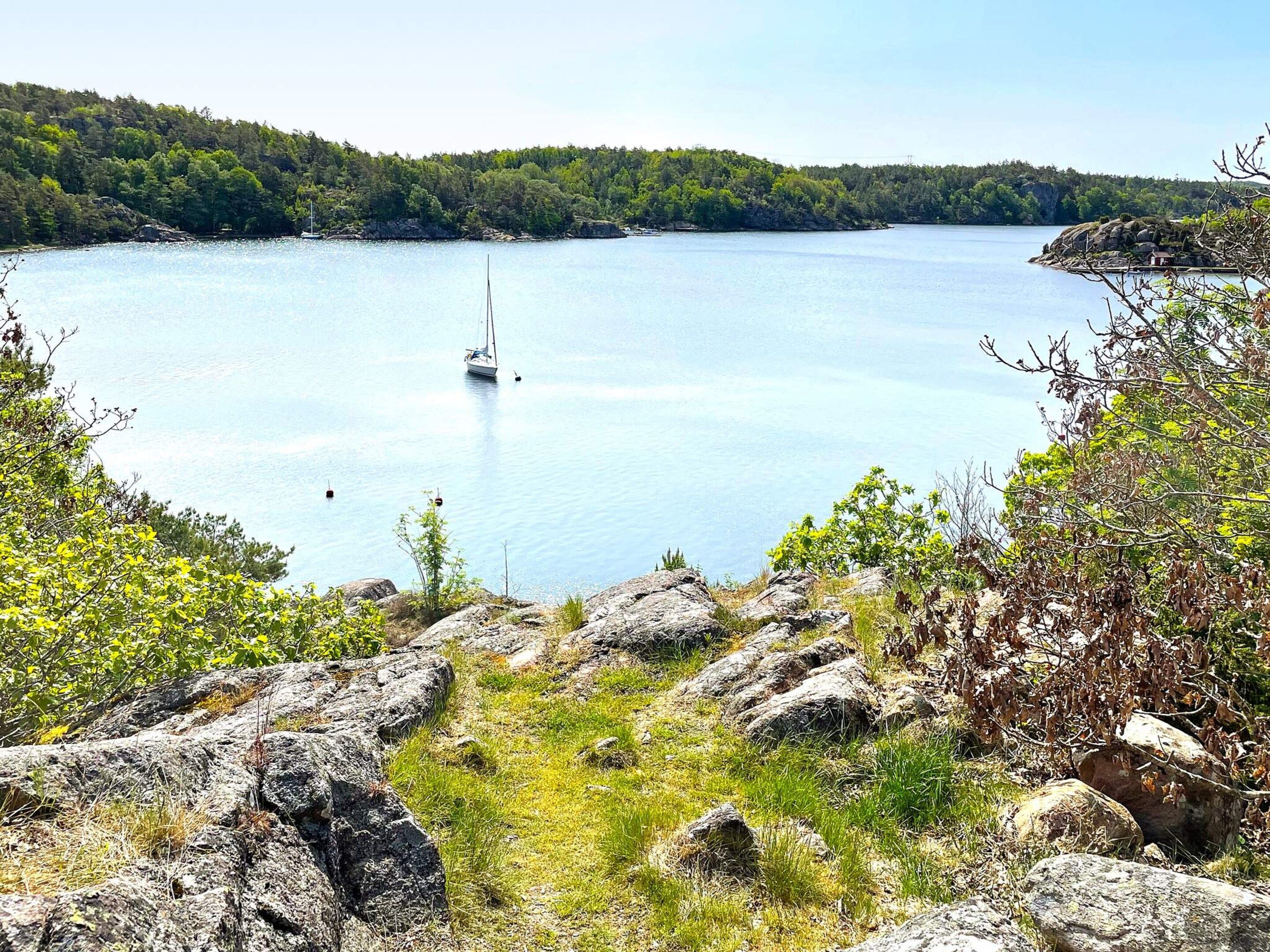 A lake with a sailboat, surrounded by rocky terrain and dense forest.