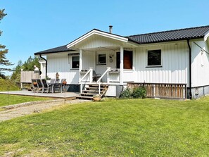 A white two-story house with a porch, a deck, and a small garden area. - 6 Person Holiday Home in Uddevalla (Uddevalla)
