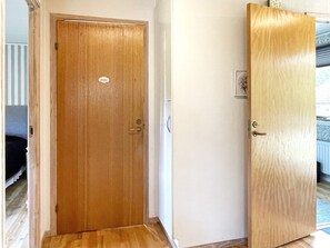 Eine Holztür mit Griff und einer kleinen Beschriftung, eine helle Wand und ein Holzboden.