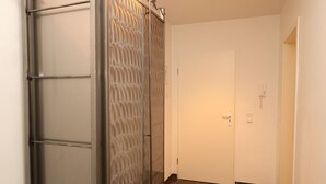 A hallway with a sliding door, a white door, and a telephone on the wall.