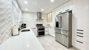 A modern kitchen with white cabinetry, stainless steel appliances, and a herringbone-patterned backsplash. - Gourmet Kitchen + Private Front Yard + Parking (San Jose)
