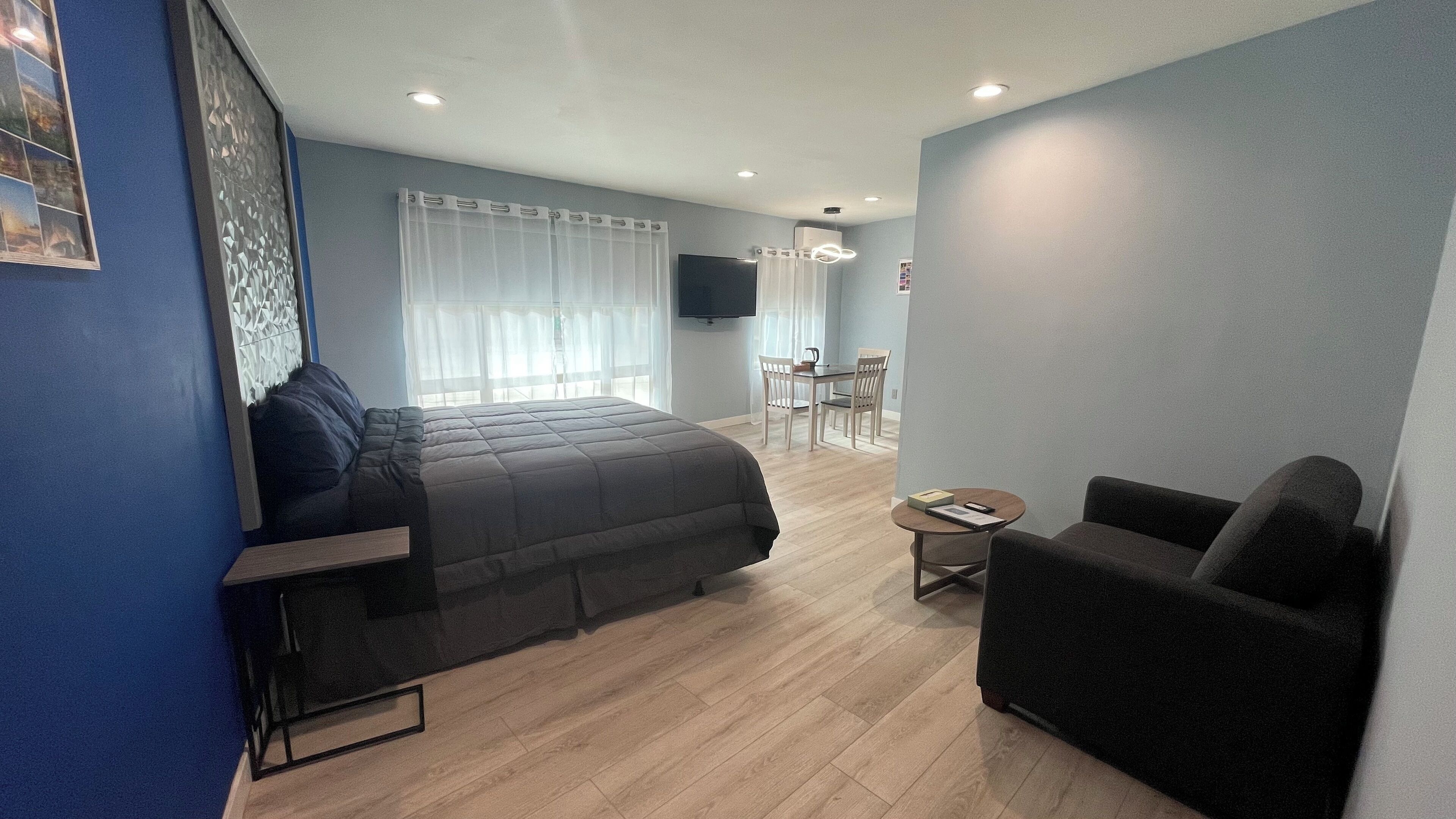 Ein modernes Hotelzimmer mit einem großen Bett, einem Sofa, einem kleinen Tisch und einem Fernseher.