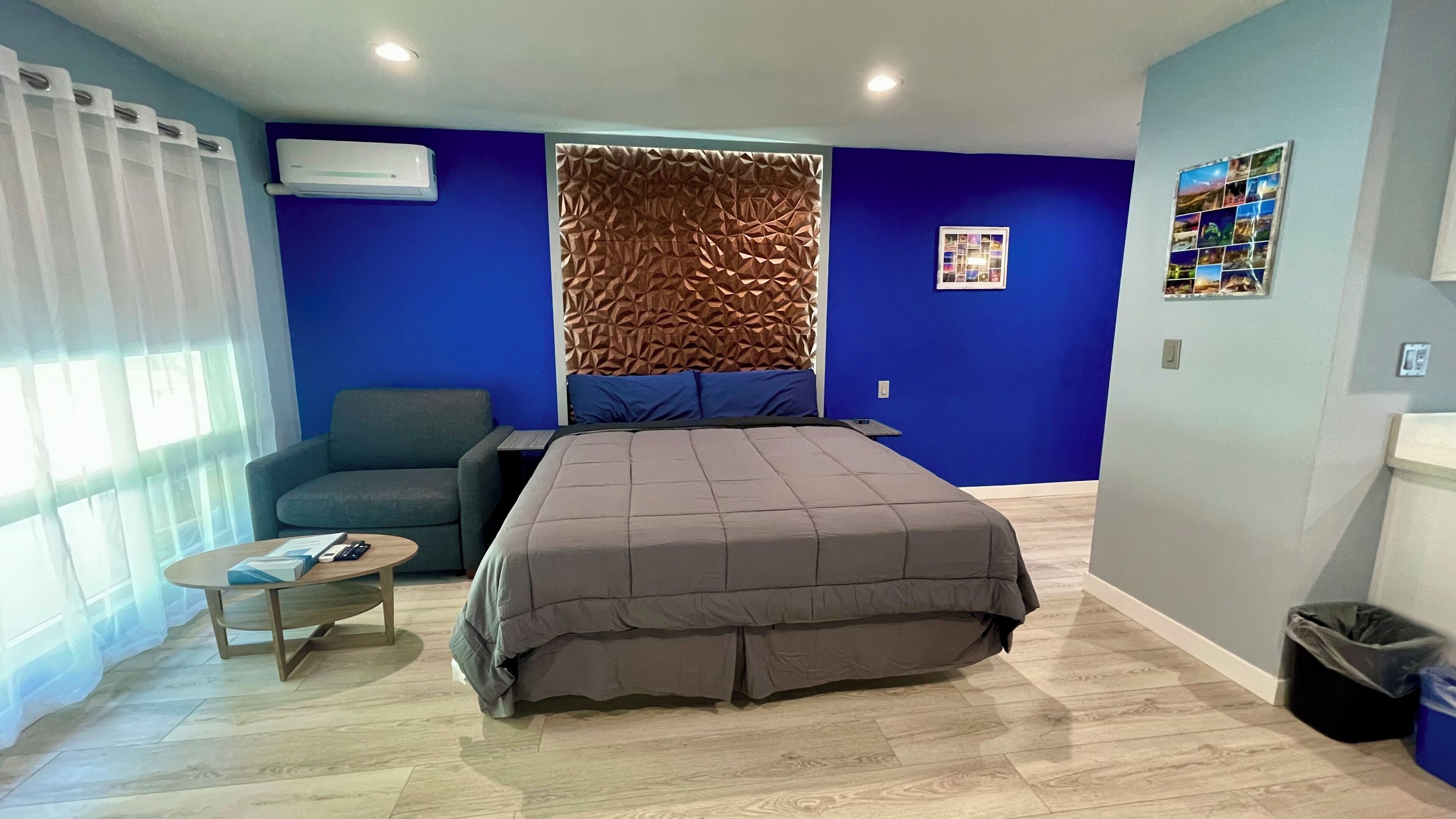 Una camera da letto moderna con un letto grande, un divano, un tavolino e un condizionatore d'aria a parete.
