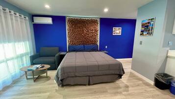 Una camera da letto moderna con un letto grande, un divano, un tavolino e un condizionatore d'aria a parete.