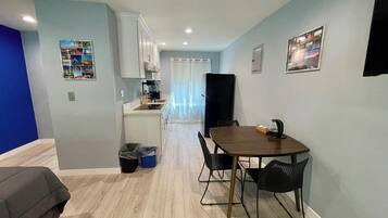 A compact living space with a kitchenette, a dining area with a table and chairs, and a small seating area with a couch.