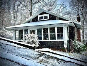 A snow-covered house with a gabled roof, large windows, and a chimney. - Bird's Eye View- Bungalow with Screened-in Porch and Fireplace (French Lick)