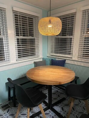 A dining area with a round wooden table, black chairs, and a woven pendant light. - Bird's Eye View- Bungalow with Screened-in Porch and Fireplace (French Lick)