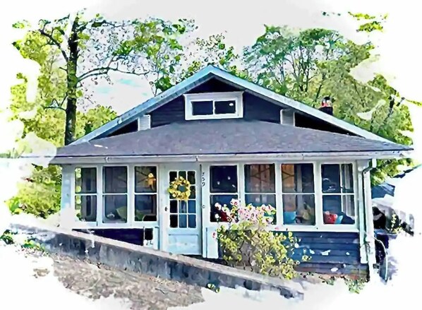 A two-story house with a gabled roof, a front porch with a railing, and a small garden area with flowers. - Bird's Eye View- Bungalow with Screened-in Porch and Fireplace (French Lick)