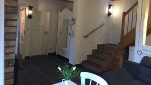A cozy interior with a staircase, a white door, and a small table with a vase of flowers. - Holiday Home Grussow (Fuenfseen)