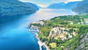 Un paisaje costero con vista despejada a un lago, colinas circundantes y un pequeño asentamiento con edificios y muelles.