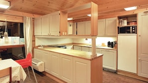 Una cocina compacta con armarios de madera, una isla central, una mesa de comedor con sillas y un refrigerador.