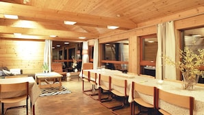 Un interior de madera con una larga mesa de comedor, varias sillas y suelo de ladrillo.