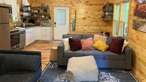 A cozy cabin interior with a kitchen, a gray sofa with colorful cushions, and a wooden ceiling. - The LucKY Lodge: Hot Tub! New Build, 11 Miles to Natural Bridge (Campton)