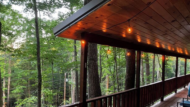 A covered outdoor deck with wooden railings, string lights, and seating areas. - The LucKY Lodge: Hot Tub! New Build, 11 Miles to Natural Bridge (Campton)