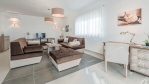 A modern living room with a sofa set, a coffee table, a TV, and a desk with a lamp. - Nicely Decorated Villa With Swimming Pool (Sukosan)