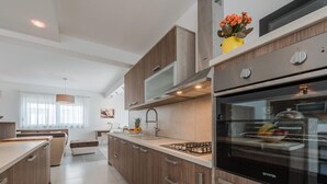 A modern kitchen with wooden cabinets, a stainless steel range hood, and a built-in oven. - Nicely Decorated Villa With Swimming Pool (Sukosan)