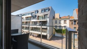 A balcony with a view of a modern building with multiple balconies and a clear blue sky.