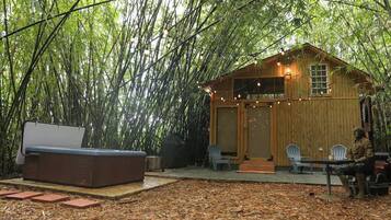 A wooden cabin with string lights, a bench, and a statue.