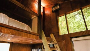 A rustic cabin with a loft bed, a ladder, and a window overlooking greenery. - HW Tiny Home Cidra (Cidra)