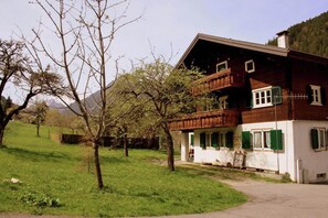 Una casa de madera tradicional con balcón, rodeada de césped y árboles.