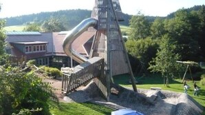 A unique outdoor sculpture with a spiral staircase and a pointed top, surrounded by a grassy area and trees. - Holiday Apartment Holzwieb (Unterkirnach)