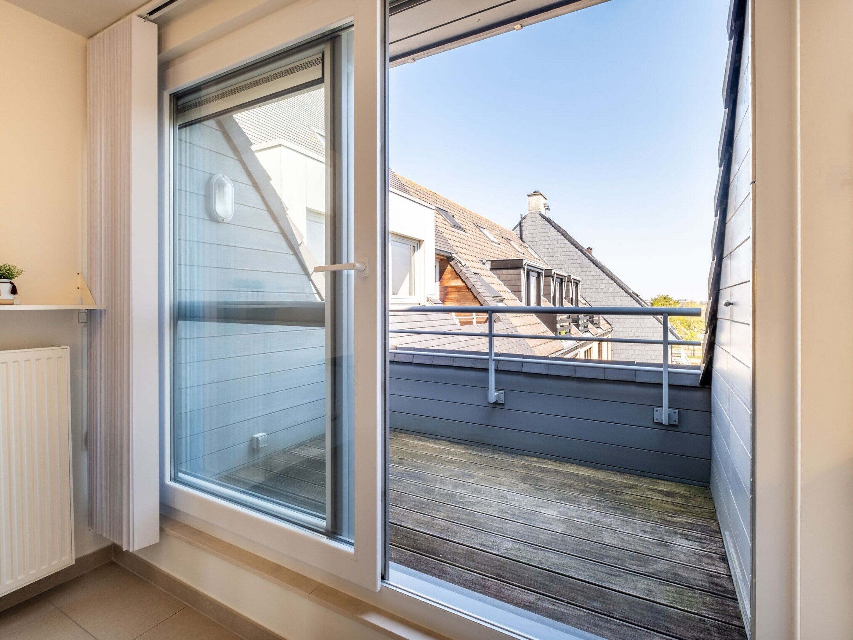 A room with a large sliding glass door leading to a balcony with a metal railing.
