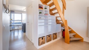 A modern interior with a wooden staircase, white shelving units, and a view to a balcony. - Coastal Retreat With Balcony (Koksijde)