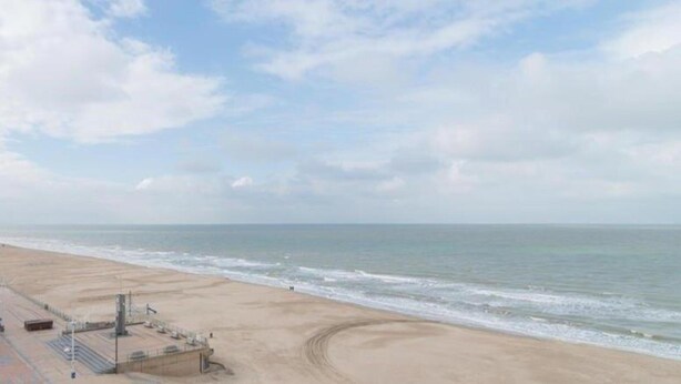 A beach with a clear sky, calm sea, and a sandy shore. - Coastal Retreat With Balcony (Koksijde)