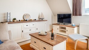 A modern living room with a wooden coffee table, a television, and a seating area. - Coastal Retreat With Balcony (Koksijde)