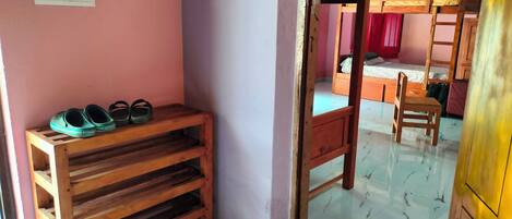 Una estantería de madera con zapatos y una cama litera con escalera.