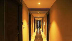 A hotel hallway with a polished floor, doors on both sides, and a light source at the end. - Cosmos Westend City Centre (Udaipur)