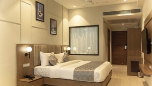 A modern hotel room with a large bed, bedside lamps, a flat-screen TV, and a ceiling fan. - Cosmos Westend City Centre (Udaipur)