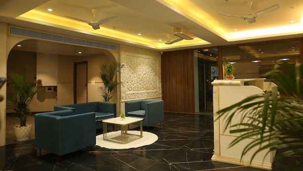 A modern lobby with blue sofas, a white reception desk, and ceiling fans. - Cosmos Westend City Centre (Udaipur)