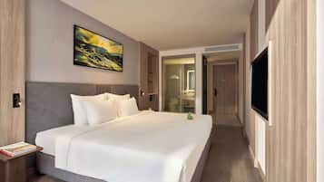 A modern hotel room with a large bed, a flat-screen TV, and a painting on the wall.