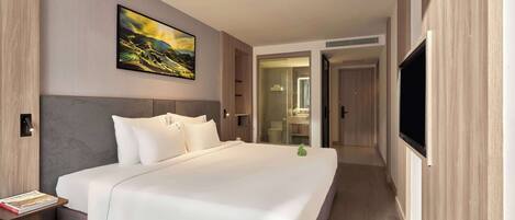 A modern hotel room with a large bed, a flat-screen TV, and a painting on the wall.