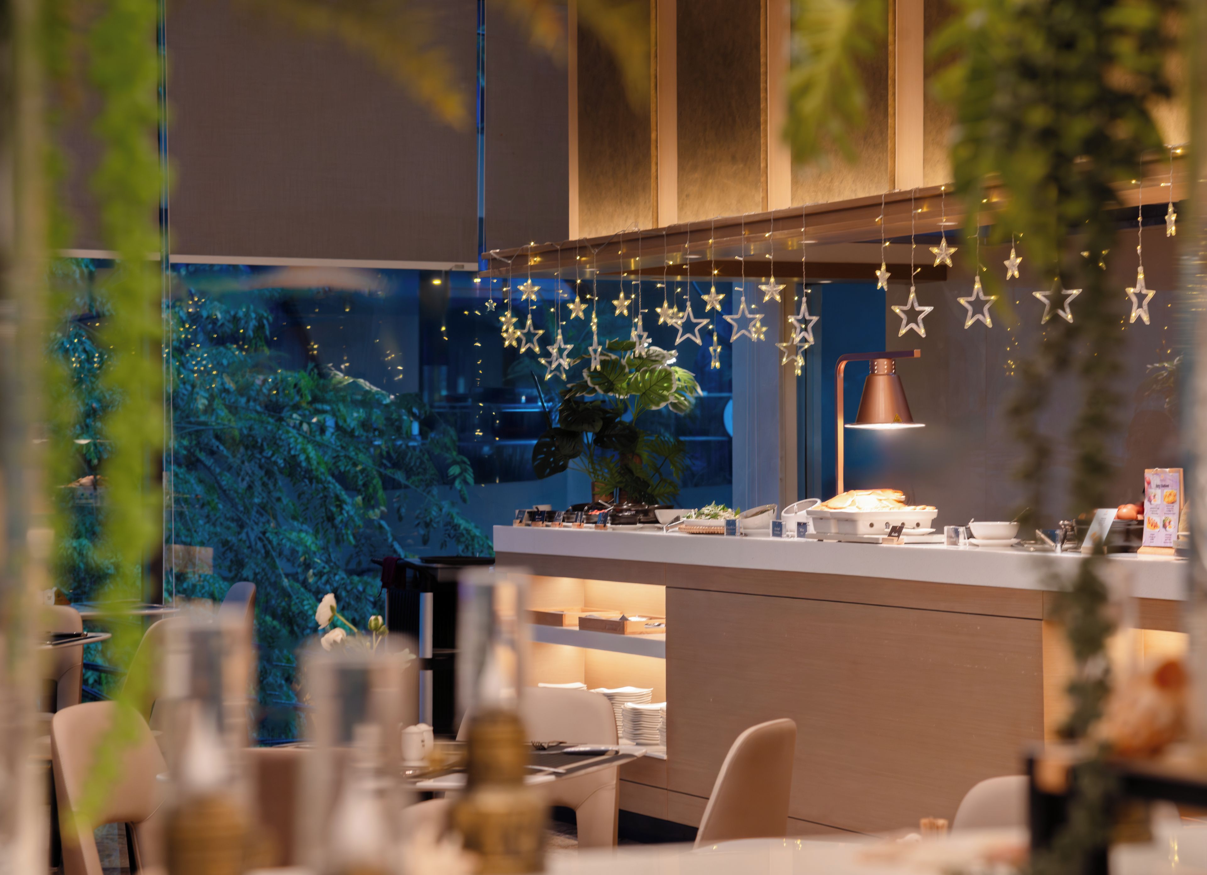 A modern restaurant interior with a counter, seating area, and decorative star lights.