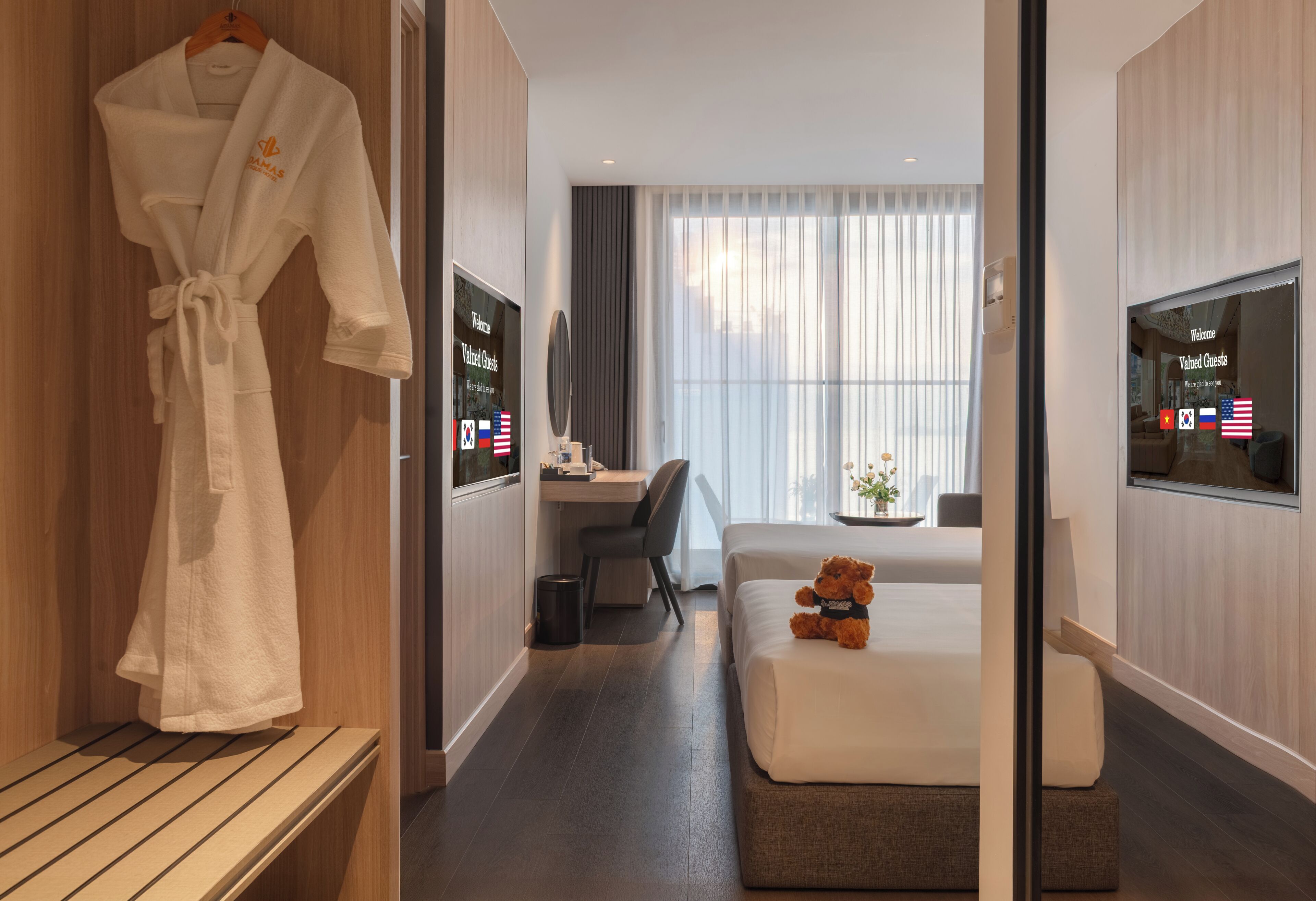 Habitación de hotel con cama, escritorio, silla, televisión y bata colgada en un perchero.