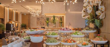 A buffet setup with various dishes and a decorative ceiling light fixture.