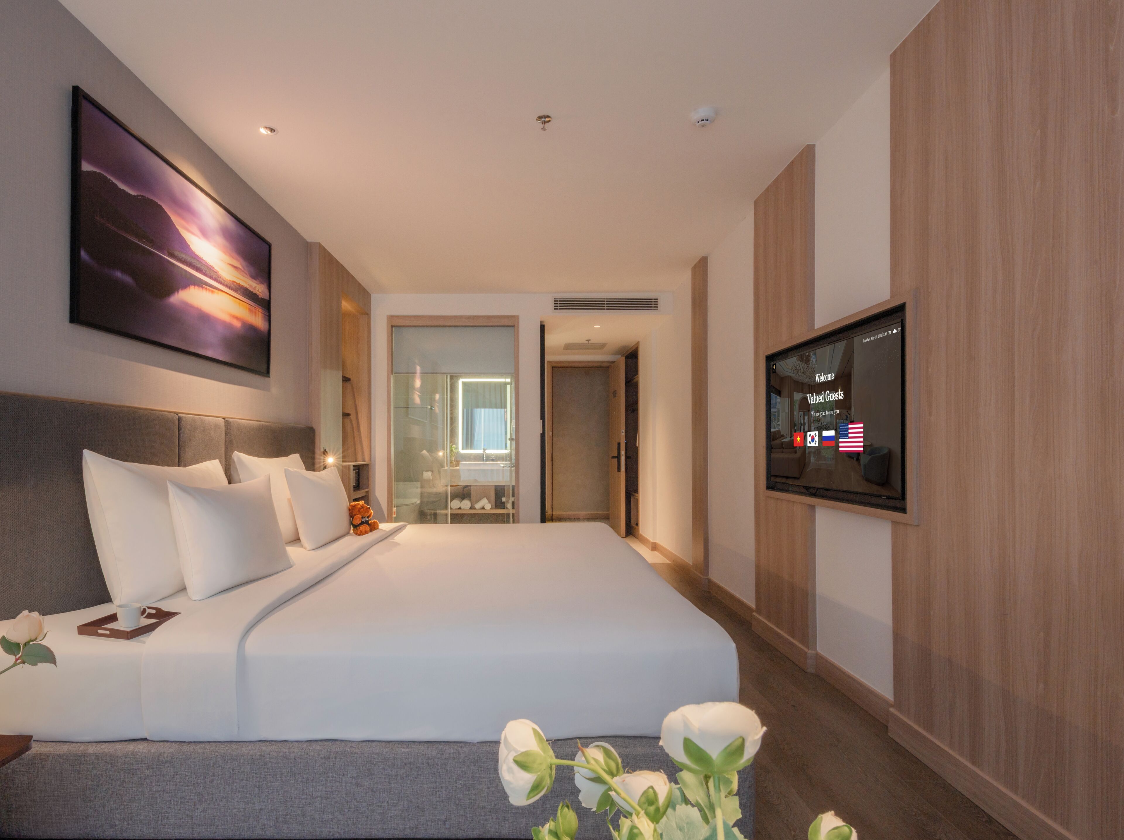 A hotel room with a large bed, a TV mounted on the wall, and a view of the hallway.