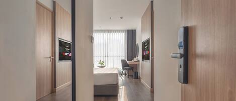 Habitació d'hotel moderna amb llit, escriptori, cadira i televisió.