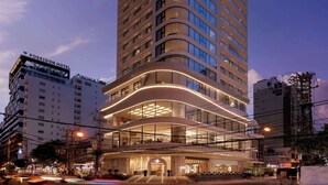 A modern hotel with a curved facade, multiple floors, and illuminated windows. - Adamas Boutique Hotel Nha Trang (Nha Trang)