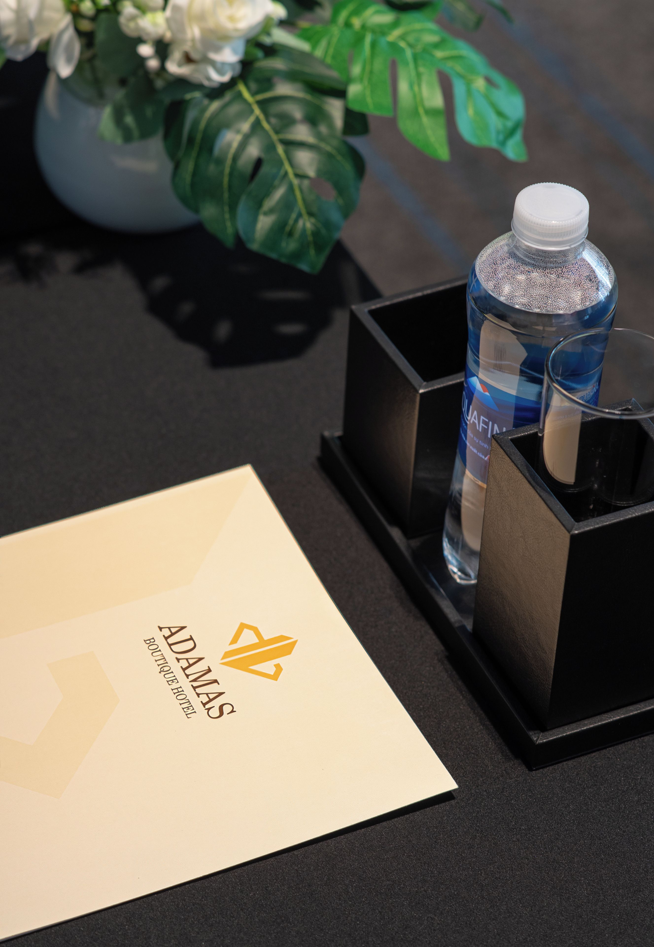 A hotel room with a water bottle, a glass, and a menu on a table.