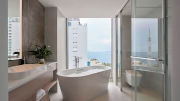 Ein modernes Badezimmer mit einer freistehenden Badewanne, einem Waschtisch mit Spiegel und einer Zimmerpflanze.